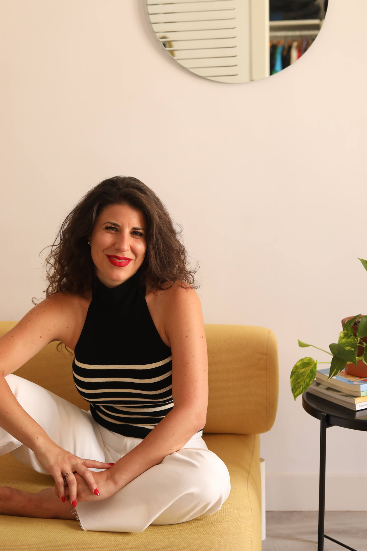 Portrait of Christine Bobba seated on a yellow chair in a bright studio